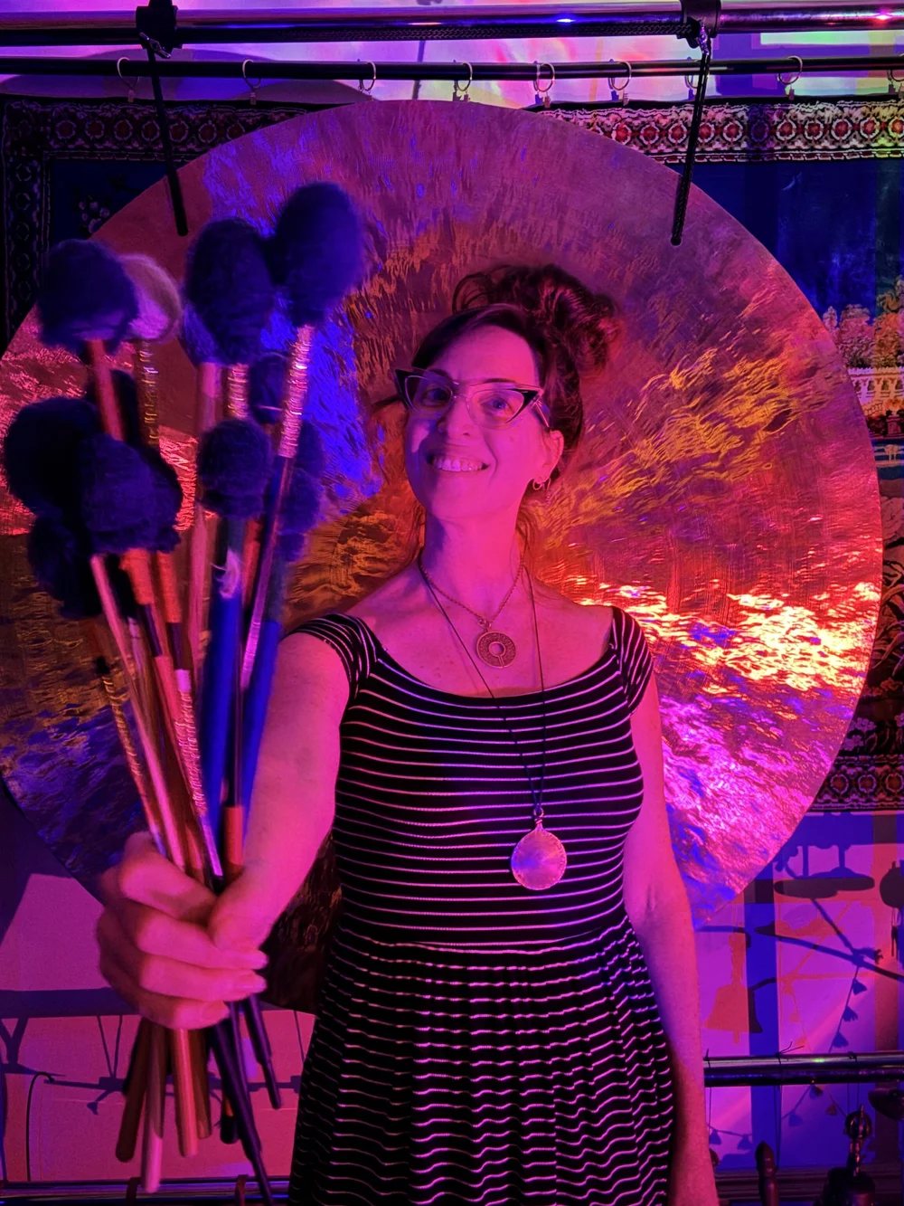 Monica Mullen holding a bundle of gong mallets in front of a gong