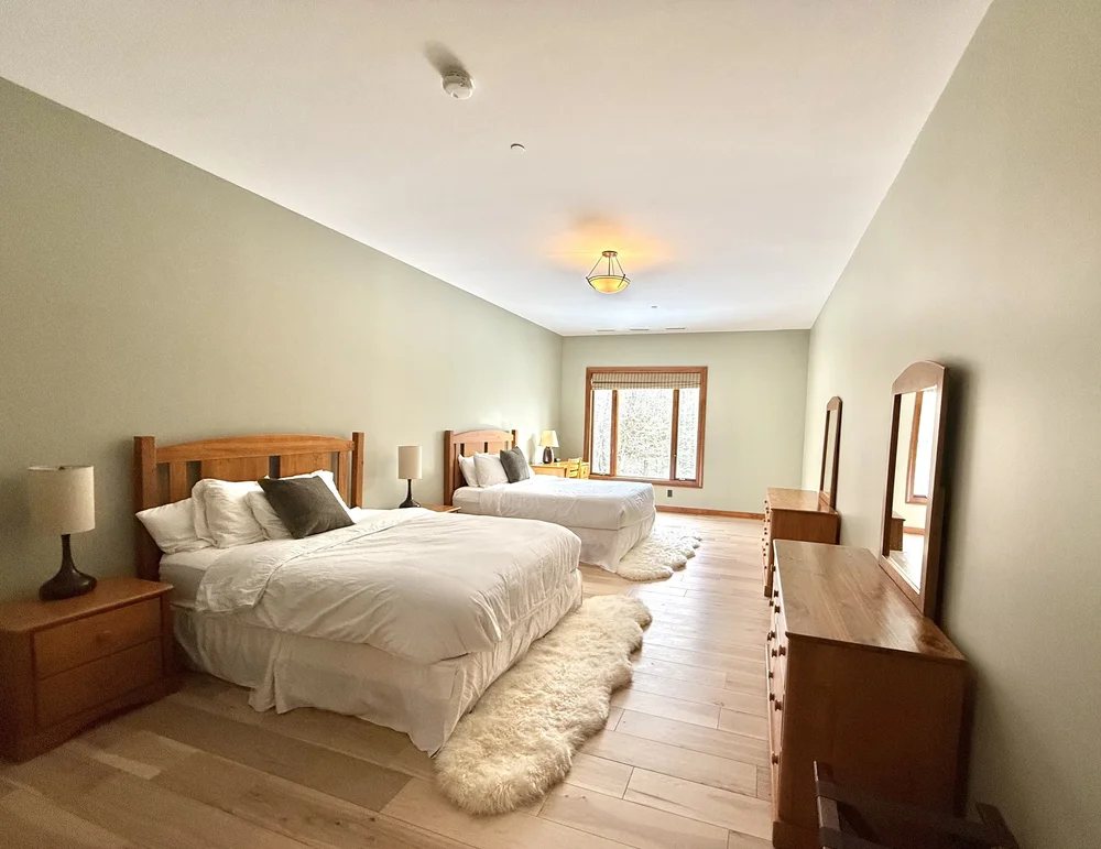 A bright guest room with two beds in the Mountain House