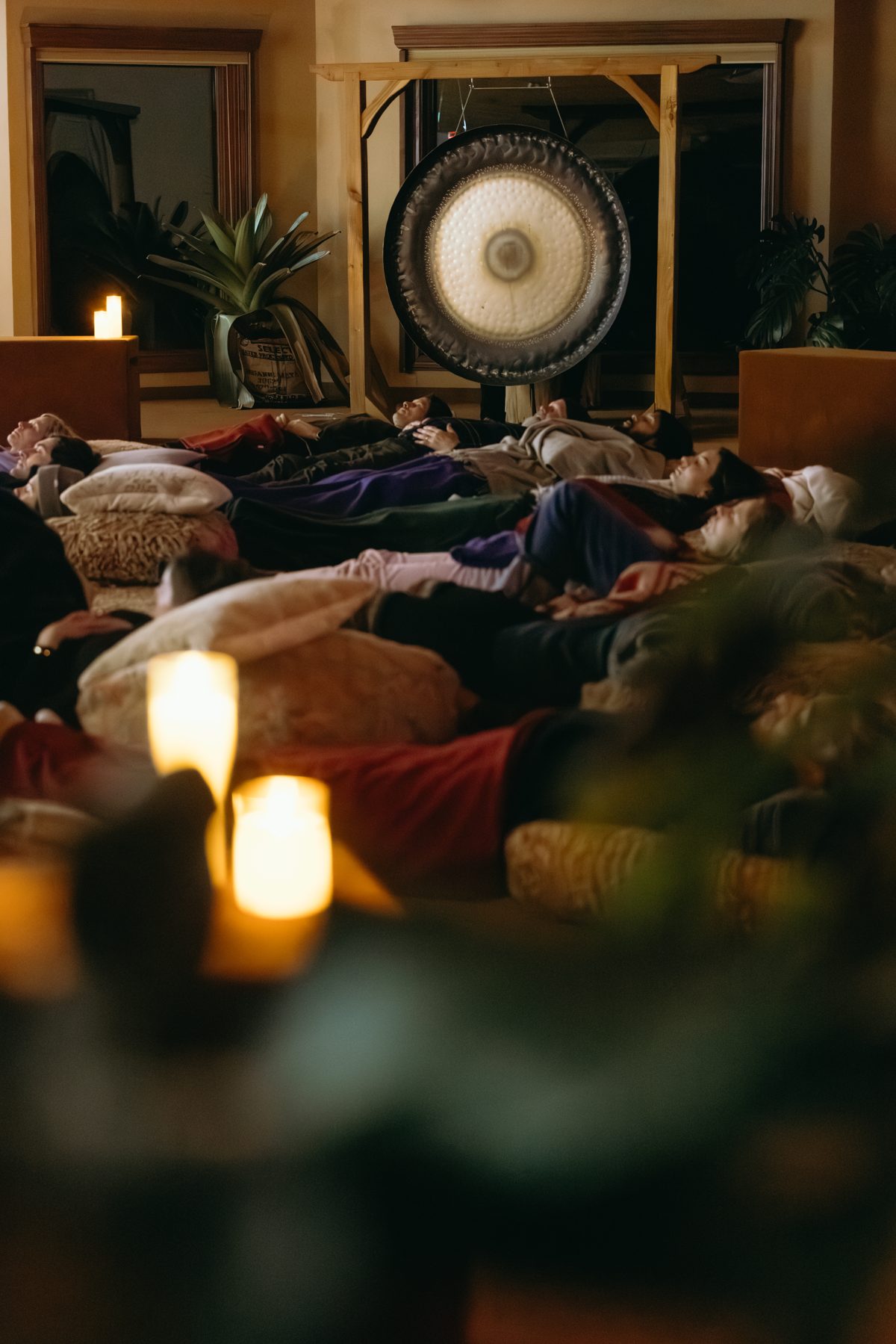 Guests resting on cushions by candlelight during a gong meditation