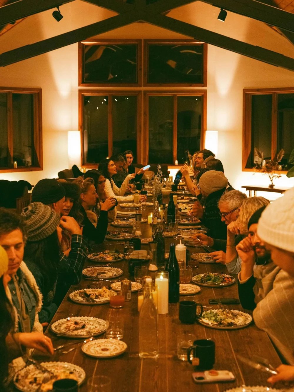 Guests sharing dinner at a long candlelit table
